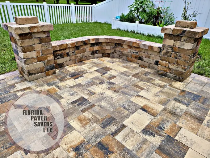 Curved stone seating wall with capped pillars beside a multicolor paver patio