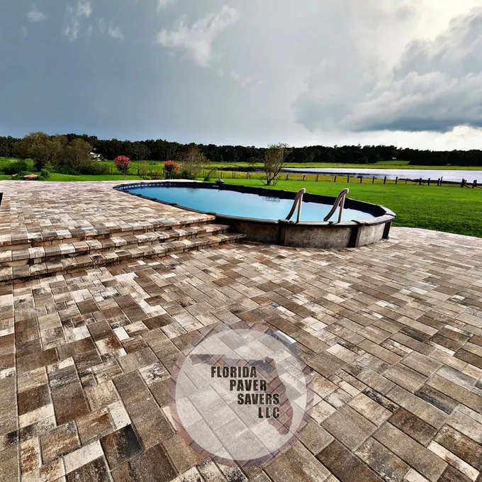 Wide multicolor paver surround beside an above-ground pool