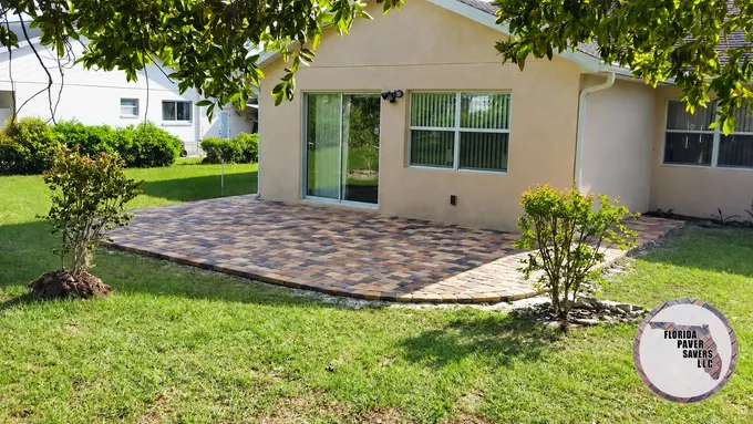 Curved paver patio outside sliding doors on a white home