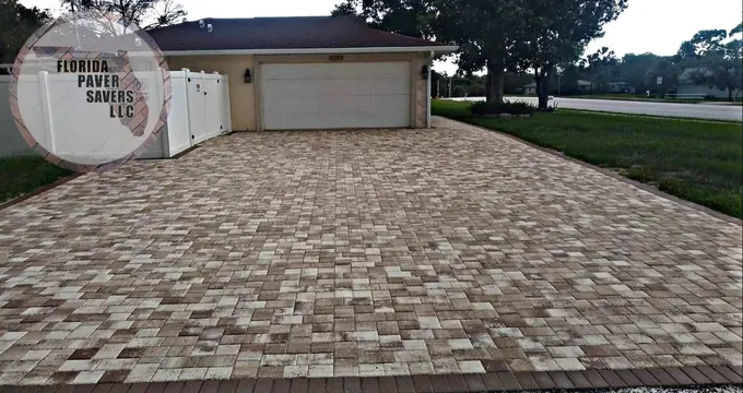 Wide multicolor paver driveway in front of a two-car garage