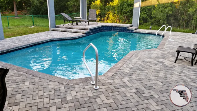 Gray paver pool deck inside a screened enclosure