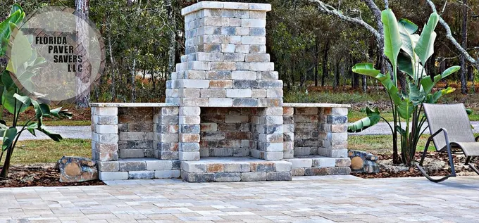 Outdoor stone fireplace with a tall chimney on a paved terrace