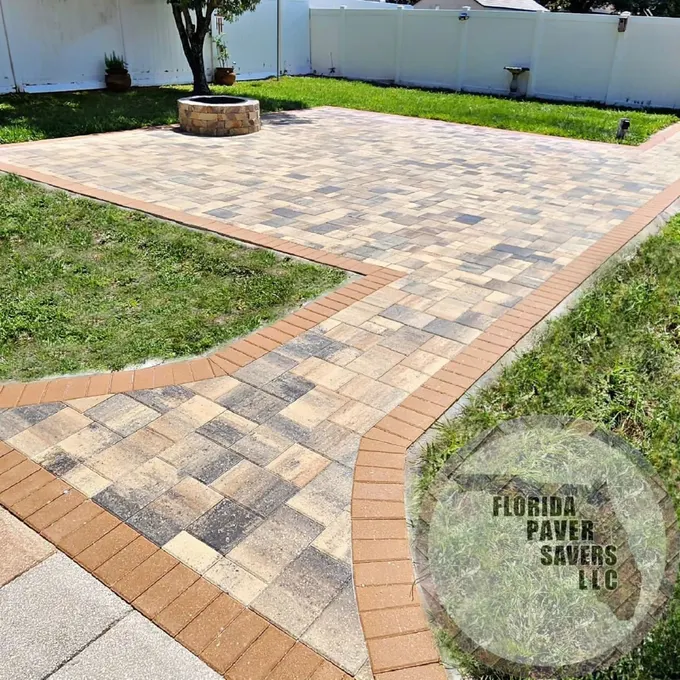 Paver walkway opening into a backyard patio with a contrasting border
