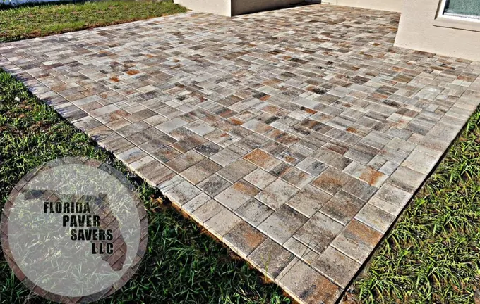 Rectangular multicolor paver patio beside a house and lawn