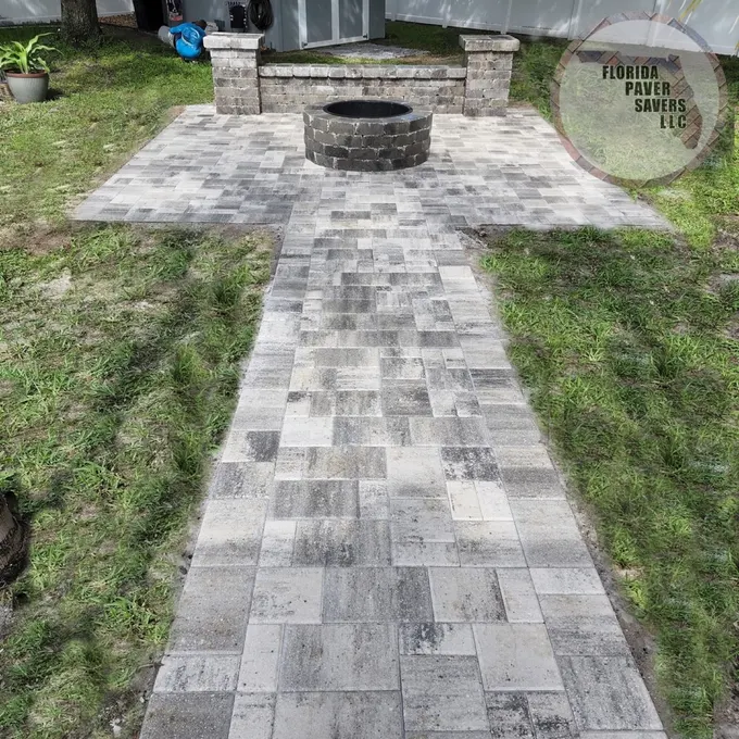 Paver path leading to a fire pit and backyard seating wall