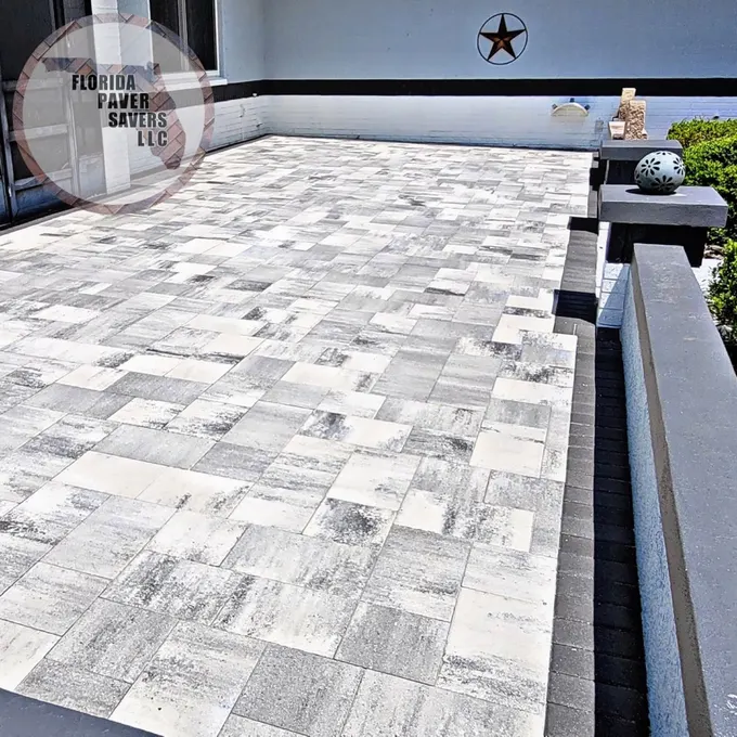 Light gray paver terrace with a low wall and contrasting dark caps