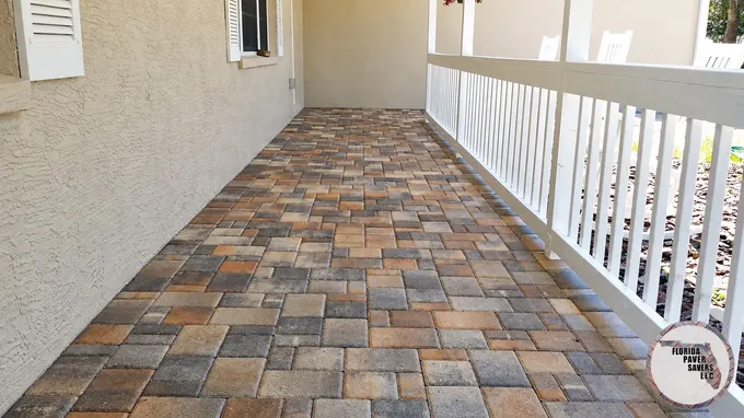 Multicolor pavers on a covered porch beside white railings