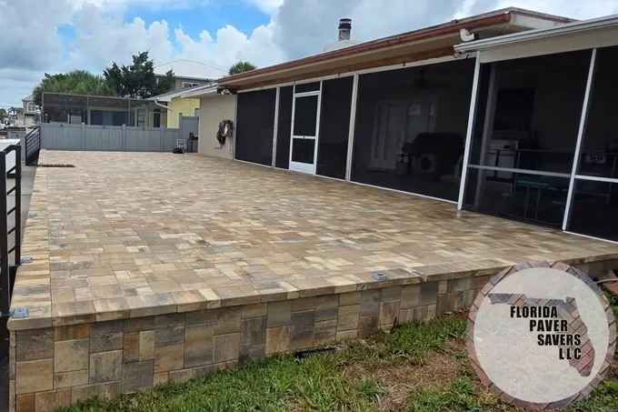 Raised multicolor paver patio with a matching wall beside a screened lanai in Hernando Beach