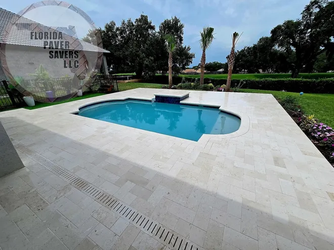Light travertine pool deck surrounding a blue swimming pool in Citrus Hills