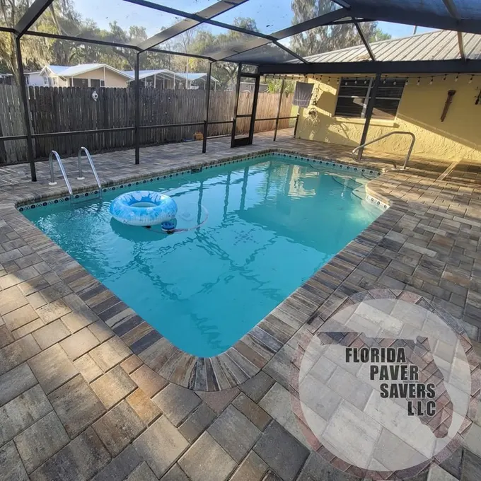 Multicolor paver deck around a pool inside a screened enclosure