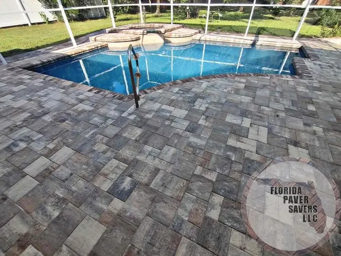 Gray and tan paver deck around a screened pool with a raised spa