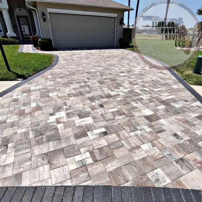 Multicolor rectangular paver driveway with dark edges approaching a garage