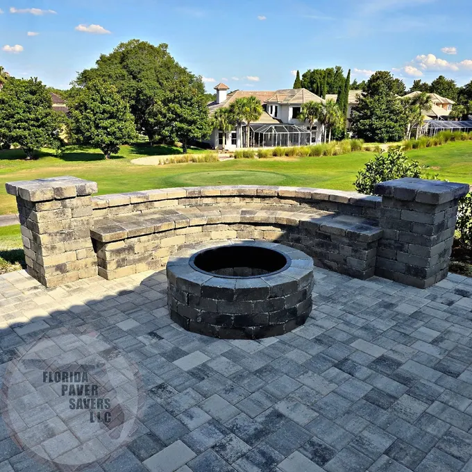 Gray stone fire pit and curved seating wall overlooking a lawn