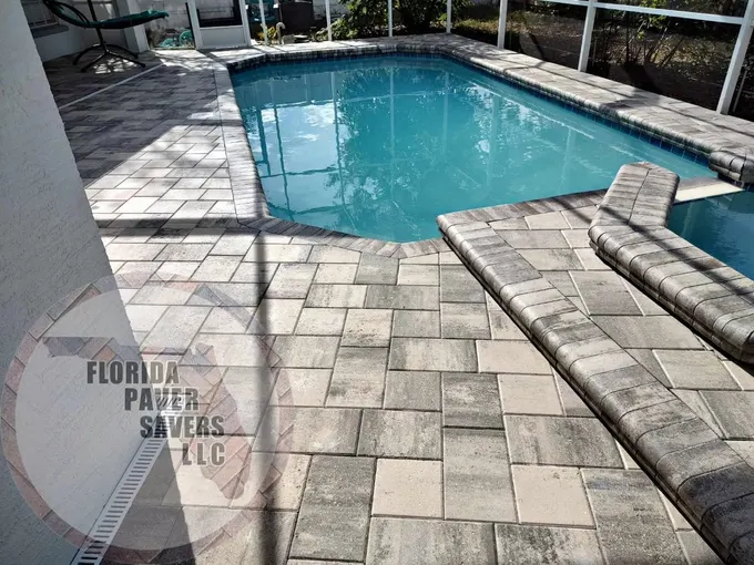Gray paver pool deck with raised spa steps inside a screened enclosure