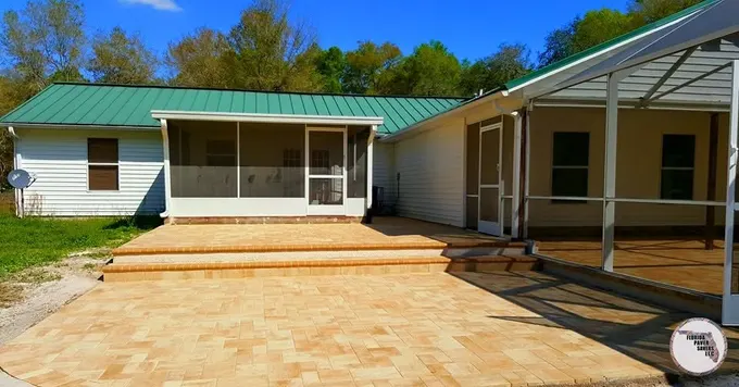 Tan paver patio and broad steps outside a screened lanai